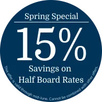 Round dark blue promotional badge in englisch featuring the text “Spring Offer”, “15% Discount on Half Board”, and a note stating that the offer is valid until mid June and cannot be combined with other offers.
