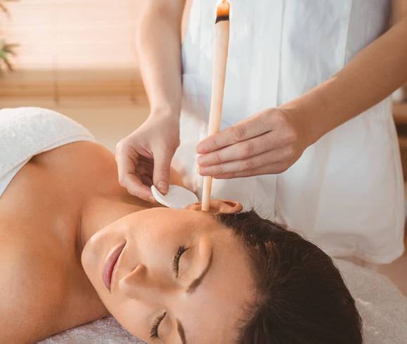 Anwendung einer traditionellen Ohrenkerzentherapie zur Linderung bei Beschwerden im Stirn-, Hals-, Ohren- und Nebenhöhlenbereich.