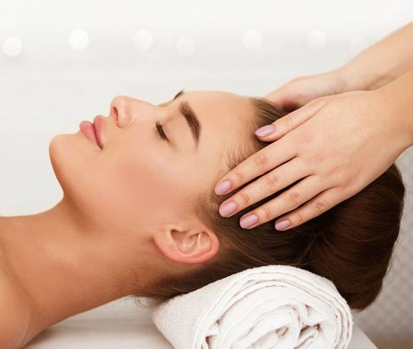 A guest receives a gentle massage on the head to relax and relieve tension.