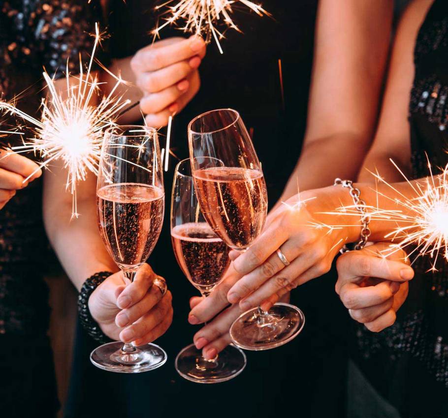 Nahaufnahme von feiernden Menschen auf der Silvesterparty im Grand Hotel Binz mit Sektgläsern und Wunderkerzen in der Hand.