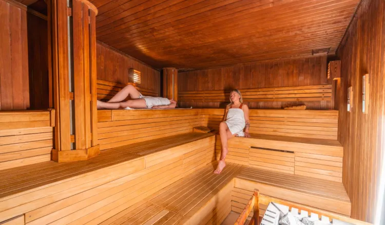 Zwei Frauen genießen die Wärme in der Sauna im Wellness im Grand Hotel Binz auf Rügen.