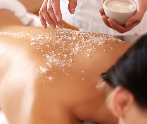 Application of a full body peeling on the back, with fine sea salt and nourishing oil for noticeably soft skin.