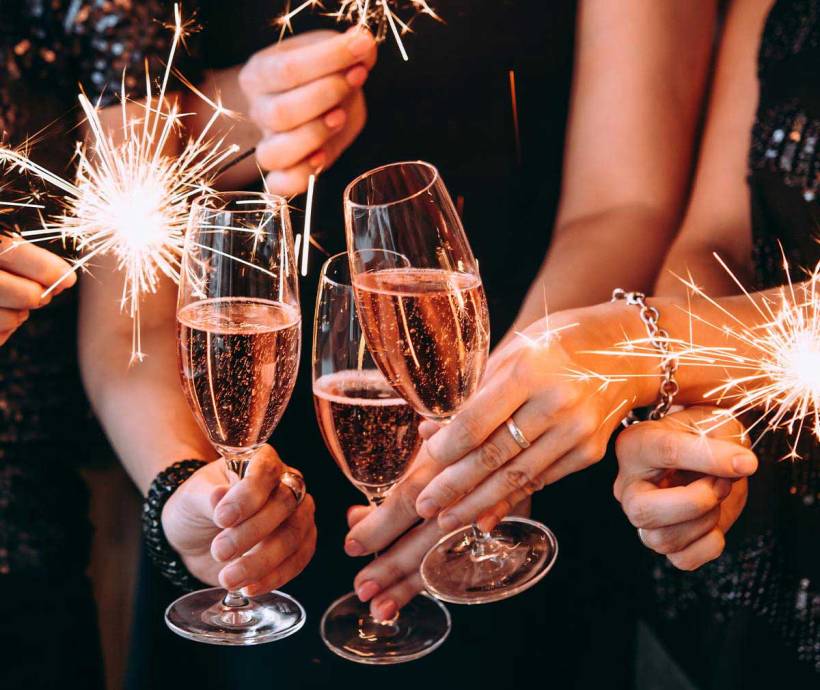 Nahaufnahme von feiernden Menschen auf der Silvesterparty im Grand Hotel Binz mit Sektgläsern und Wunderkerzen in der Hand.
