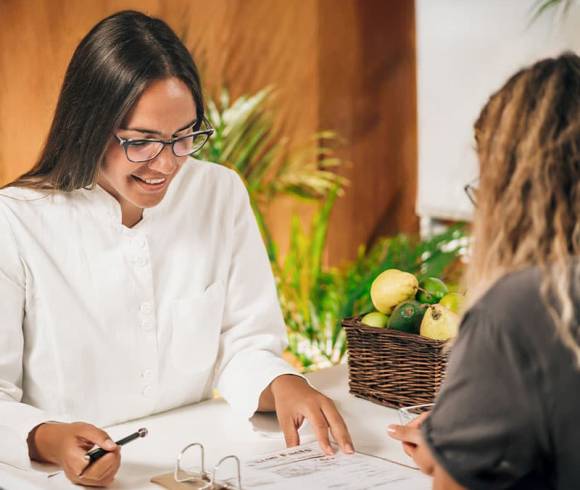 Eine Ayurveda-Ärztin berät ihre Kundin anhand von Unterlagen.