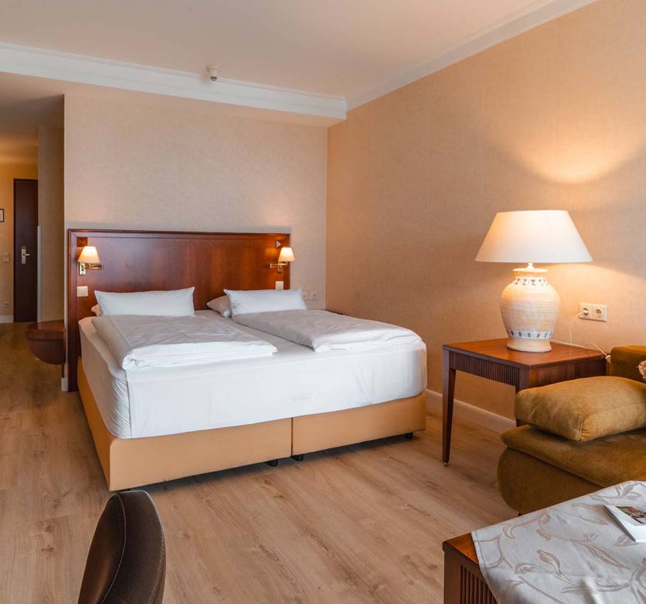 Comfortable Baltic Deluxe Room at the Grand Hotel Binz with cozy sitting area, balcony, and panoramic view of the Baltic Sea.