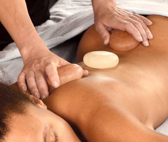 Wellnessbehandlung mit Himalaya-Salzsteinen auf dem Rücken zur Muskelentspannung.
