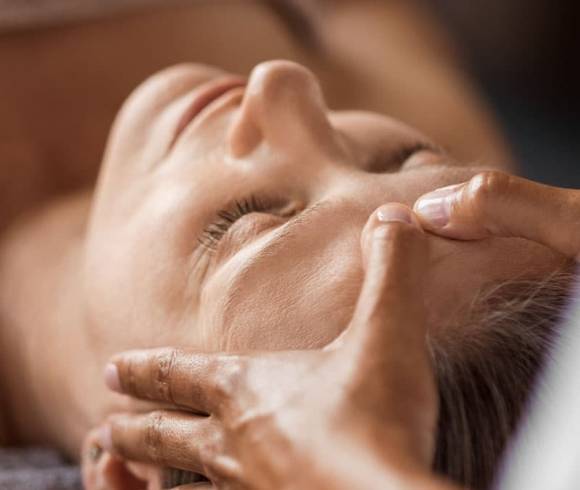 Gezielte, wohltuende Massagegriffe am Kopf eines entspannten Gastes.