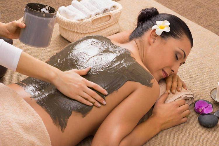 Frau genießt eine entspannende Schlammpackung beim Wellness während ihrer Fasten-Kur im Grand Hotel Binz auf Rügen.
