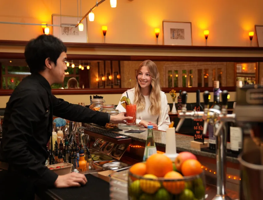 Barkeeper serviert einem Gast einen Cocktail an der Bar im Grand Hotel Binz.