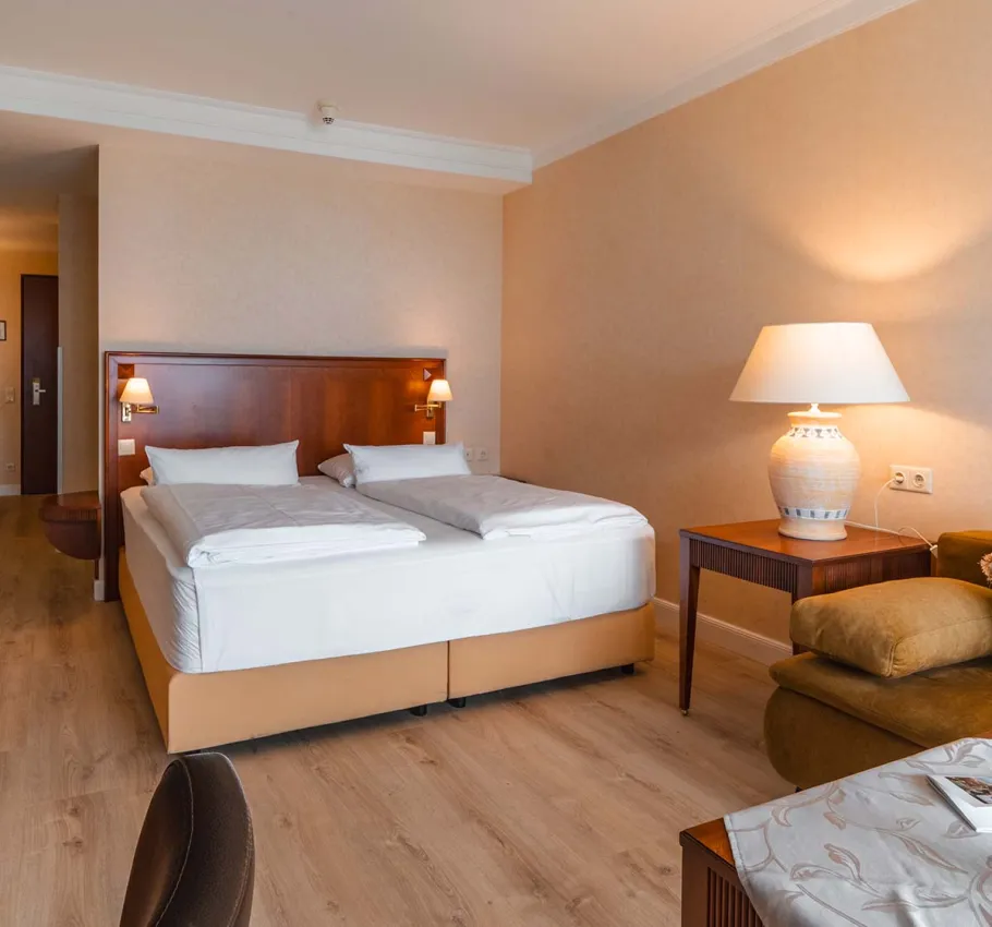 Comfortable Baltic Deluxe Room at the Grand Hotel Binz with cozy sitting area, balcony, and panoramic view of the Baltic Sea.