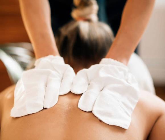 Eine Frau erhält eine Rückenmassage mit original ayurvedischen Seidenhandschuhen.