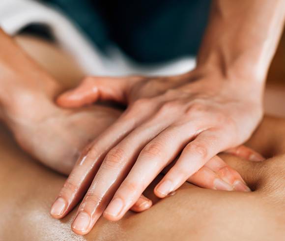 Hände, die übereinander gelegt sanften Druck bei einer ayurvedischen Massage ausüben.