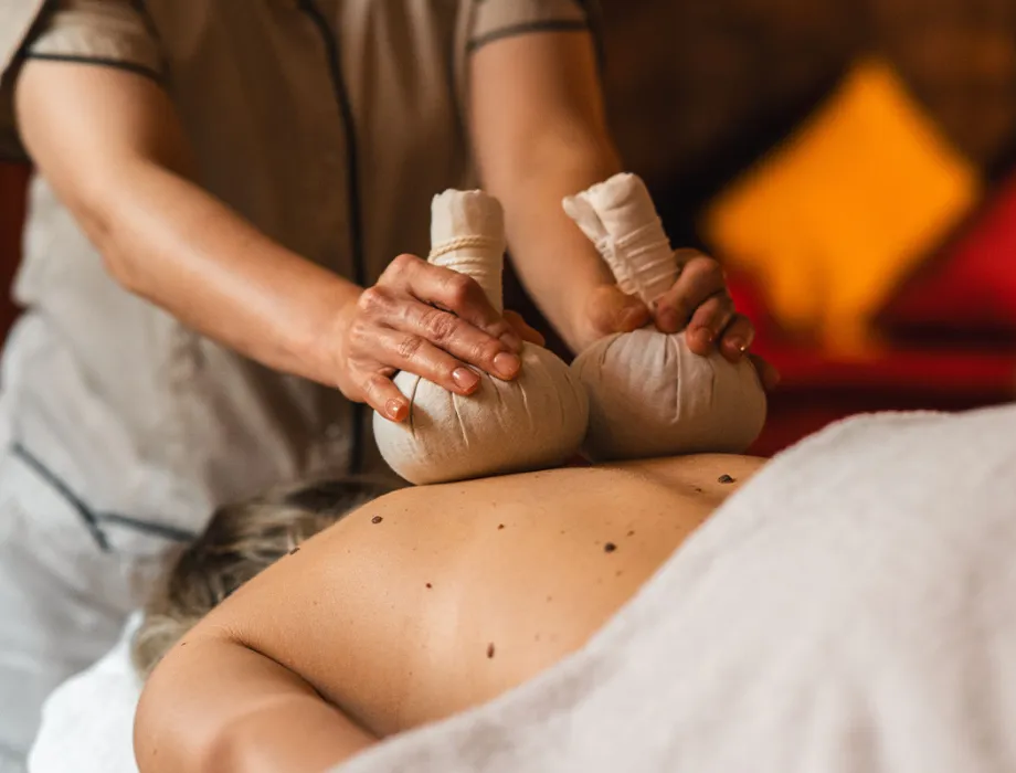 Frau bei einer ayurvedischen Kräuterstempel-Massage im Wellnessurlaub im Grand Hotel Binz mit vielen Ayurveda Angeboten.
