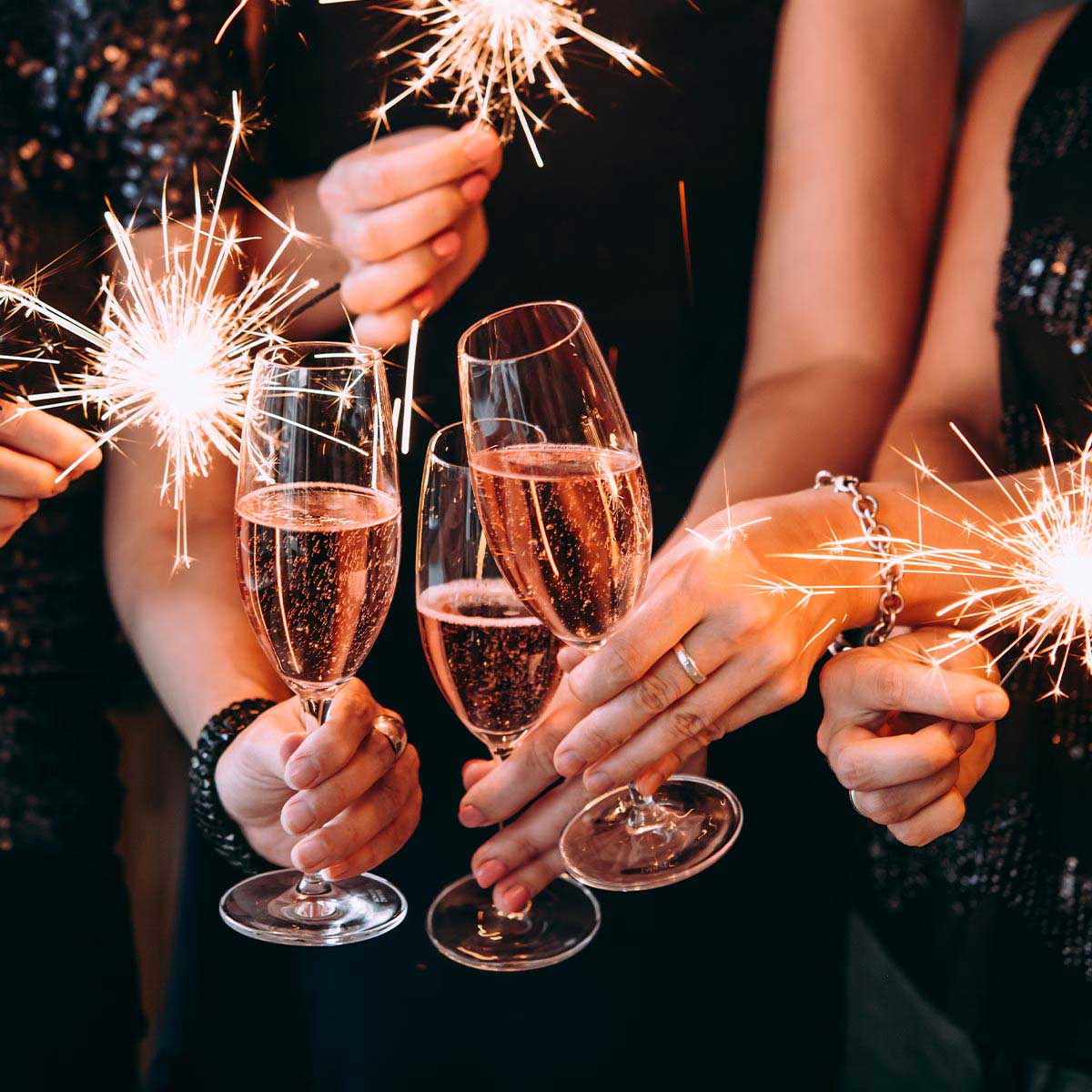 Nahaufnahme von feiernden Menschen auf der Silvesterparty im Grand Hotel Binz mit Sektgläsern und Wunderkerzen in der Hand.