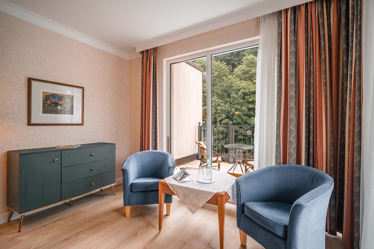 Seating area and chest of drawers in the Granitz Deluxe Room at the Grand Hotel Binz with roof terrace and view of the countryside.