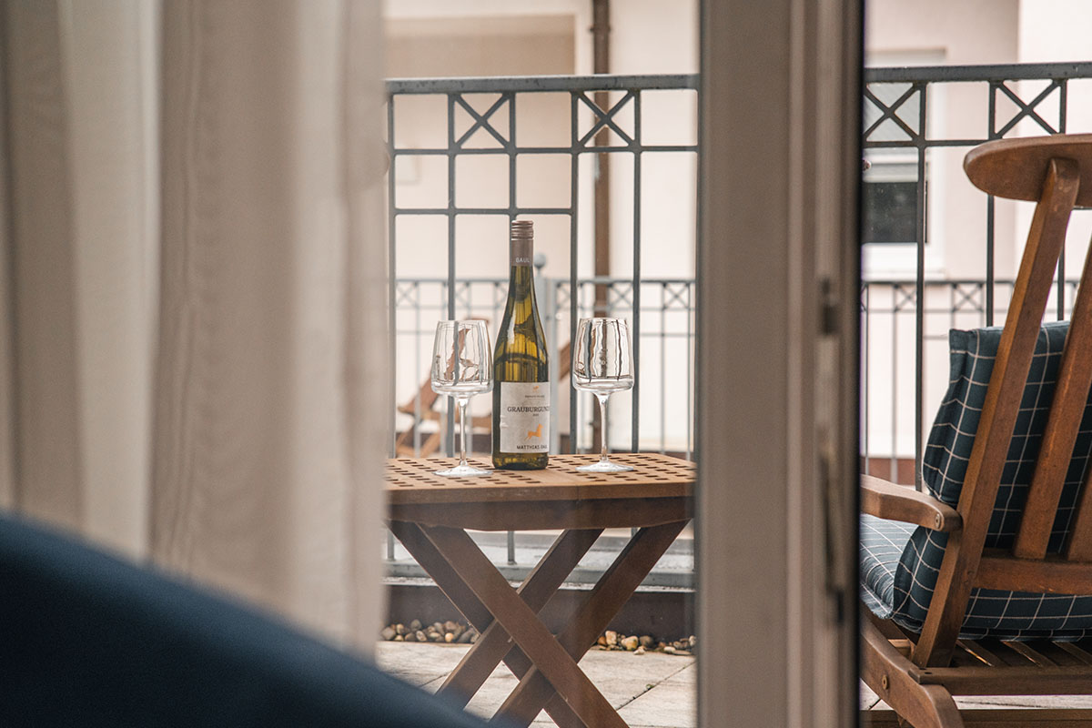 Roof terrace of the Granitz Deluxe hotel room with comfortable chairs and a bottle of wine.