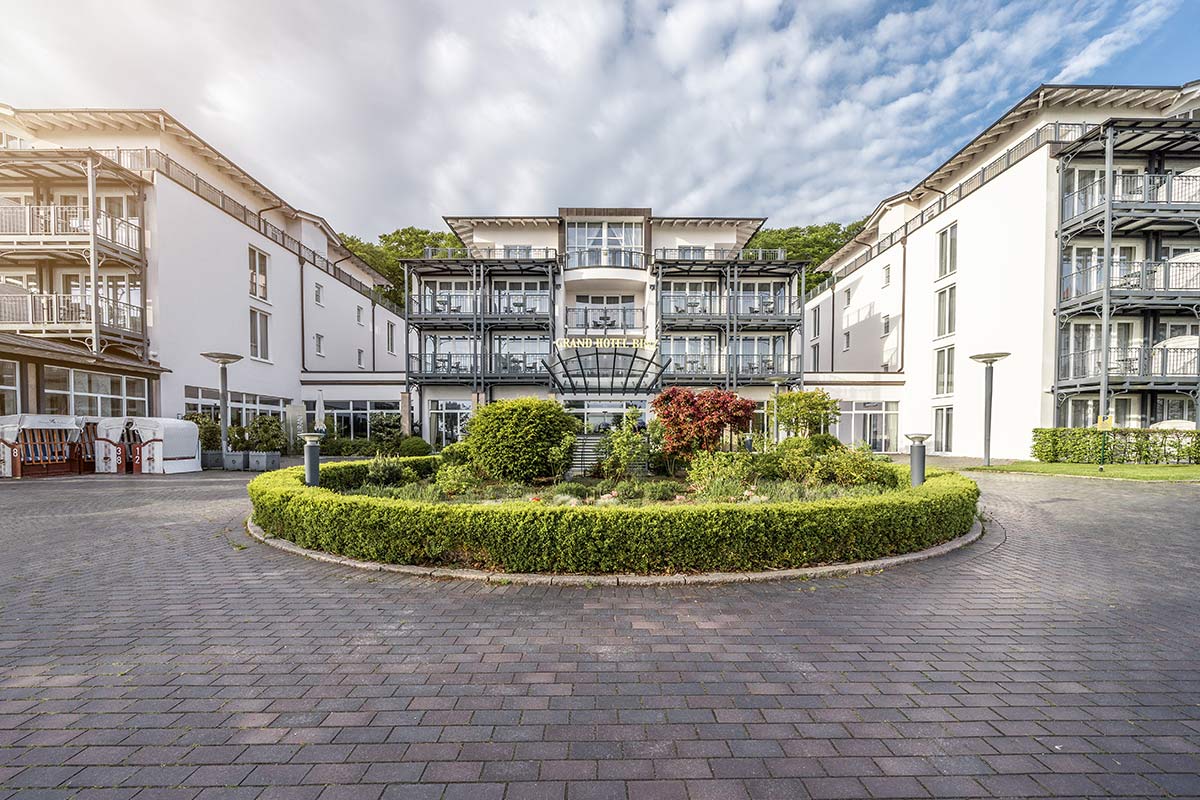Außenansicht des Grand Hotel Binz mit eleganter Fassade und gepflegter Gartenanlage an der Ostsee.