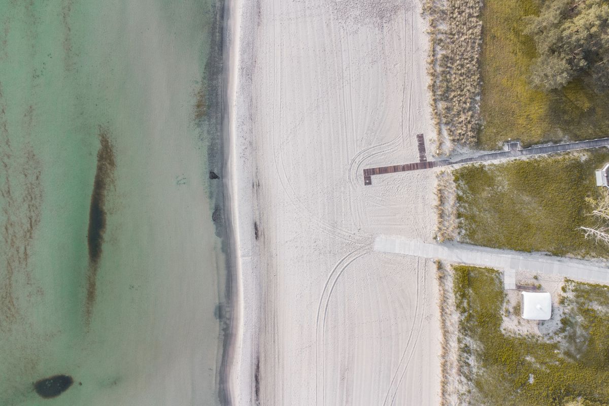 Vogelperspektive des hellen Strandabschnitts auf Rügen, mit klarem Meer und idyllischer Küstenlandschaft.