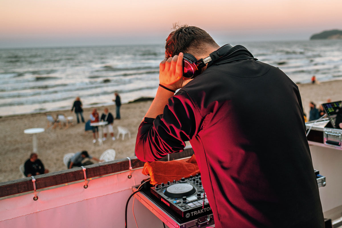 Nahaufnahme eines DJs, der auf der Saisonabschluss-Party am Strand vor dem Grand Hotel Binz auflegt und für Stimmung sorgt.