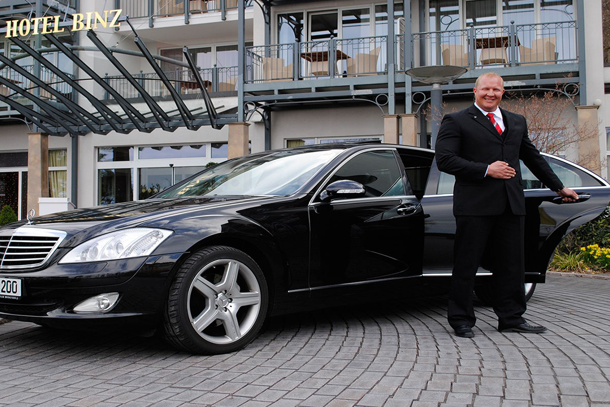 Eine schwarze Limousine vor der ein Chauffeur steht und die Tür aufhält vor dem Grand Hotel Binz